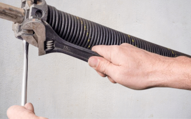 Broken spring repair with winding bar releasing torsion tension on garage door
