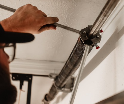 Technician performing broken spring repair on garage door torsion assembly